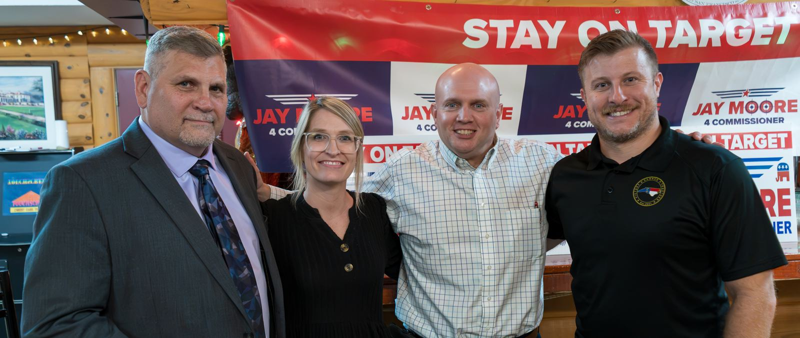 Jay Moore (center, light check shirt) with supporters under a Stay on Target banner
